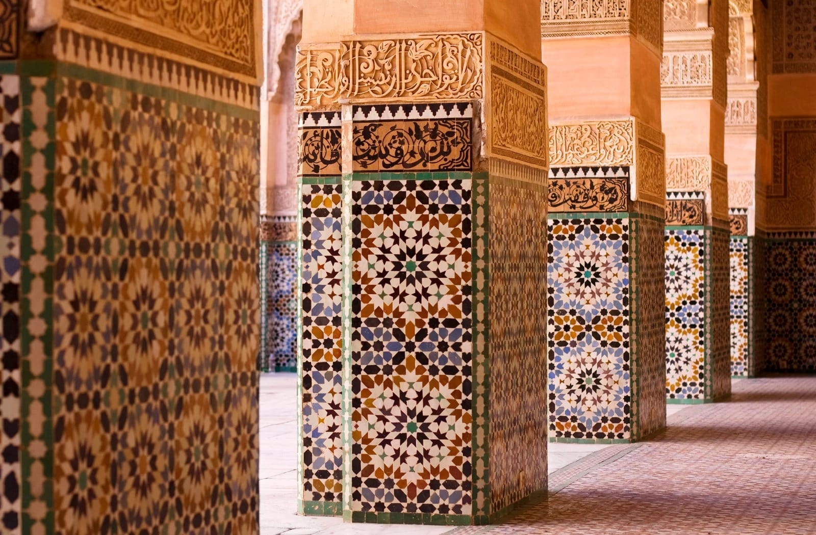 Zellige star mosaic and carved Kufic inscription bands on madrasa arcade columns
