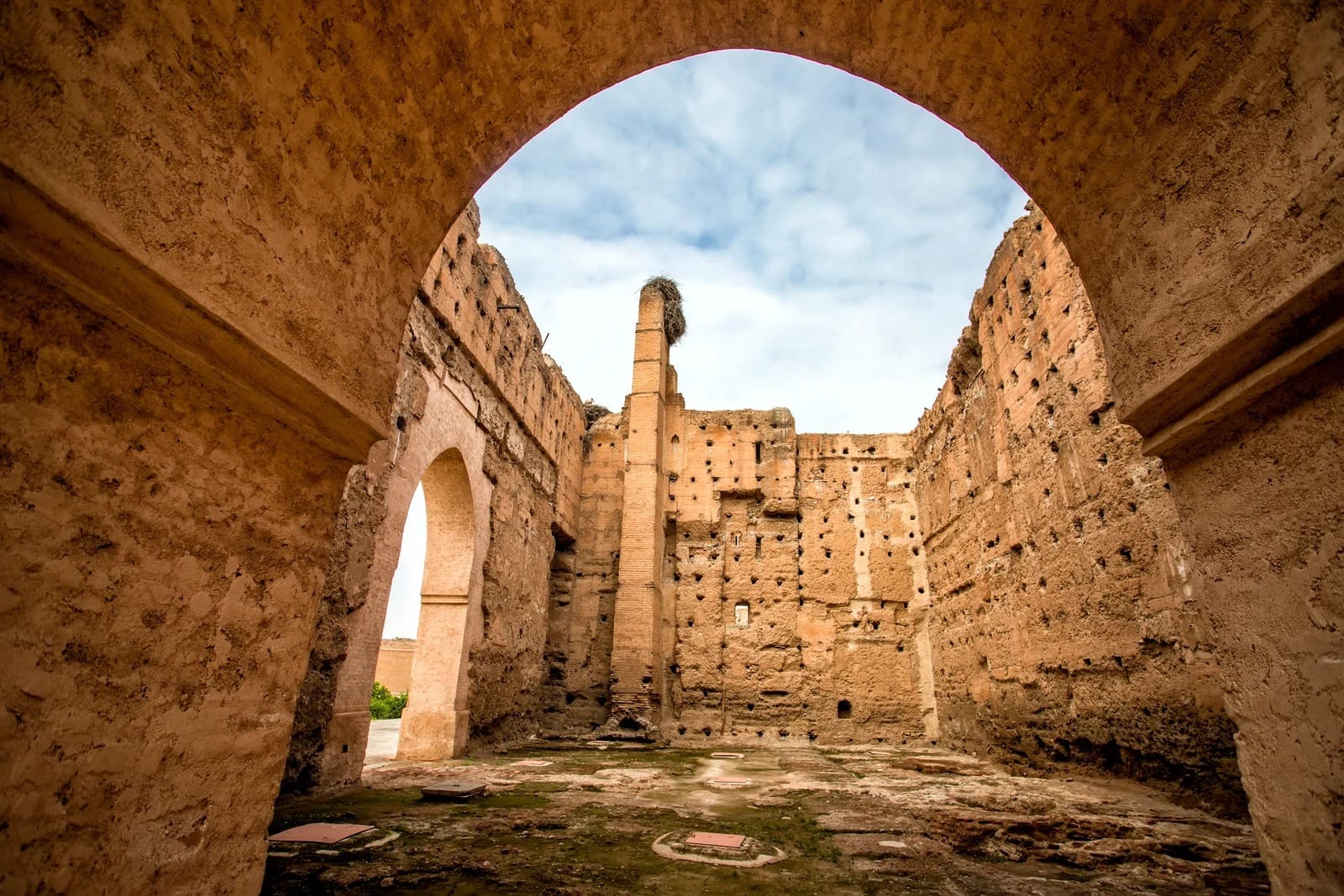 Roofless rammed-earth hall with stork nest atop brick pillar, El Badi Palace