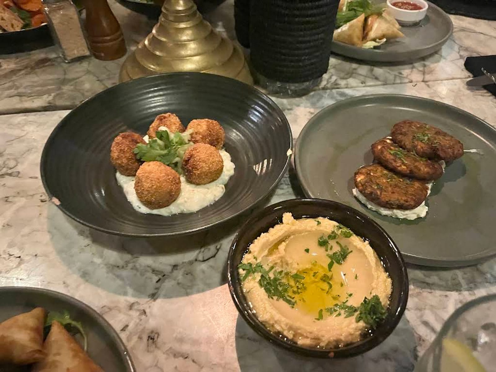 Mezze plates of falafel, kefta and hummus on a marble table at Le Jardin, Marrakech