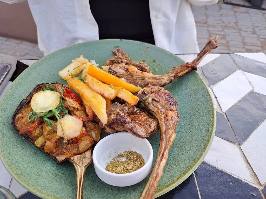 Grilled lamb chops and vegetables on a green plate at Nomad's terrace, Marrakech