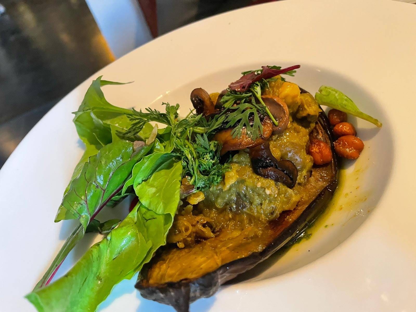 Stuffed aubergine with mushrooms, chickpeas and fresh herbs plated at Nomad Marrakech