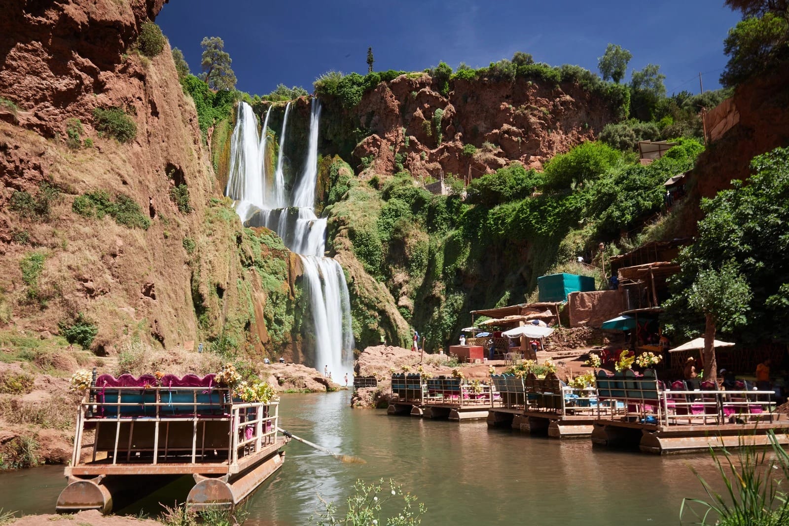 Ouzoud Falls cascading beside flower-decked rafts and cliff-side restaurants, Morocco