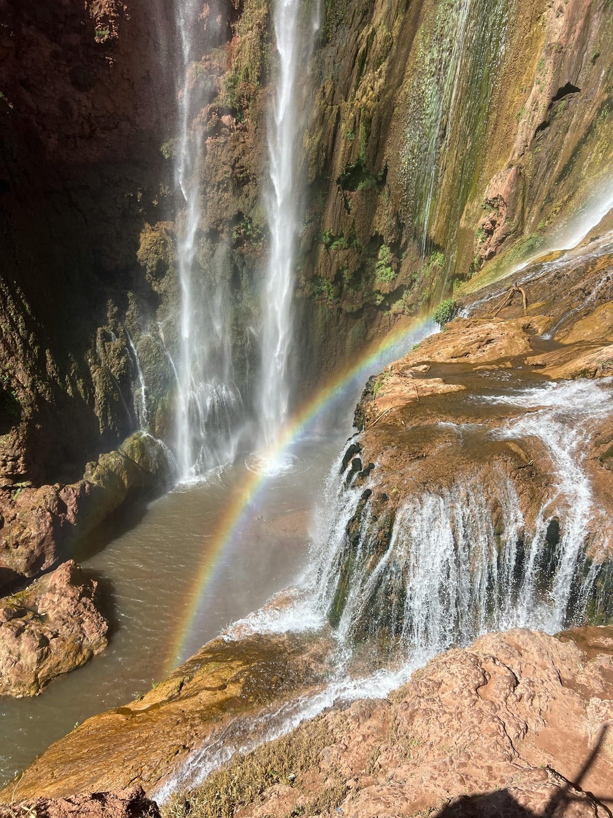 Rainbow arcing through spray above the Ouzoud Falls plunge pool, Morocco