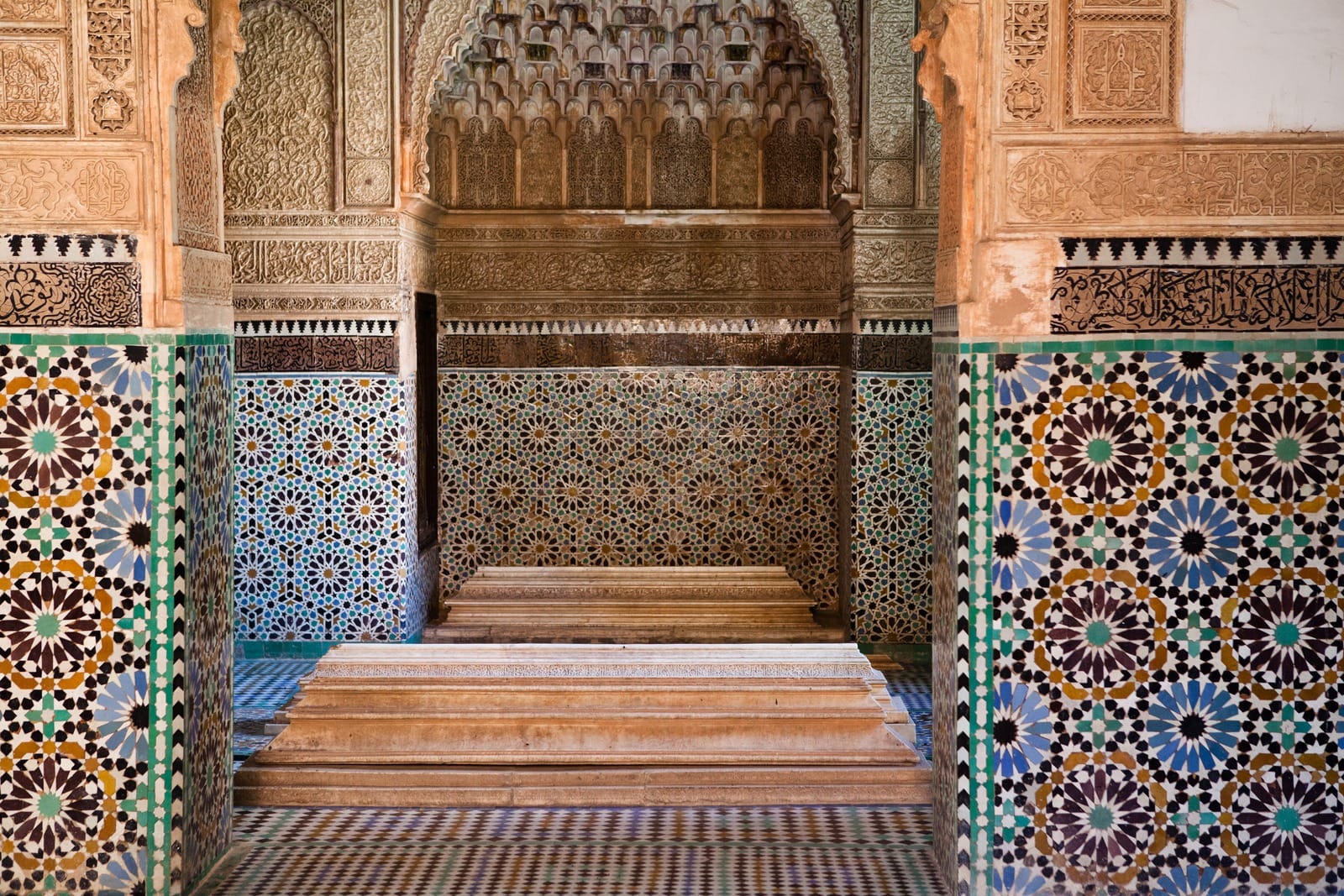 Marble tombs beneath a carved muqarnas arch and zellige tilework, Saadian Tombs Marrakech